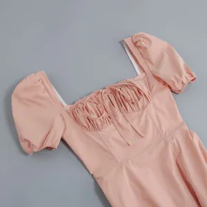 Detail view of a pink French-style dress featuring puff sleeves and an elegant bow neckline