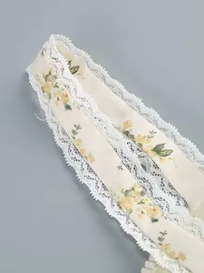 Detailed close-up of a floral print dress strap featuring delicate white lace trim edges
