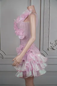 Detailansicht eines rosa Bühnenkleids mit schimmernden Rüschen und feinen Perlen.
