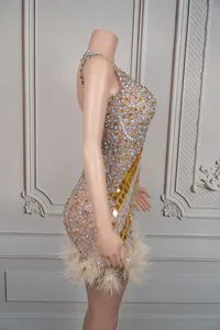 Side view detail of a luxury rhinestone mini dress with gold mirror pieces and beige feather trim