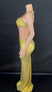 Detailed side view of a gold cutout evening gown featuring decorative rhinestone chains