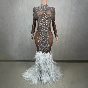 Elegante abito da sera in mesh marrone con strass e orlo a sirena in piume bianche.