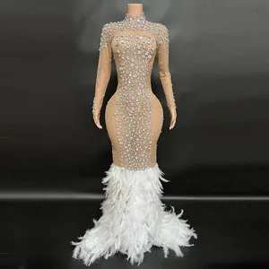 Vista detallada del vestido de noche de malla nude con pedrería y plumas blancas.