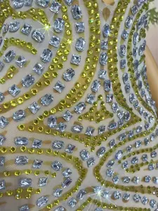 Close-up view of intricate yellow and clear rhinestones on sheer mesh party dress fabric
