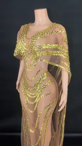 Close-up detail of gold sequin mesh evening gown featuring elegant cape design and V-neck