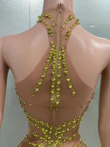 Detailansicht von grünen Strasssteinen auf hautfarbenem Netzkleid mit Reißverschluss.