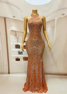 Detailweergave van luxe oranje galajurk met strassteentjes en halternek, vloerlengte