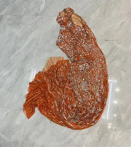 Gedetailleerde macro-weergave van de sprankelende strass-steentjes op oranje jurk