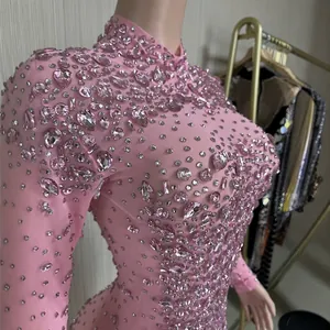Elegante abito da sera rosa in rete decorato con cristalli scintillanti su un manichino.