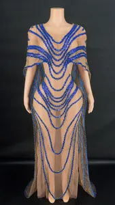 Close-up of intricate blue sequined patterns on an elegant sheer mesh gown with a cape