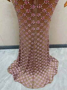 Dettaglio ravvicinato di un abito da sera in rete marrone con intricati motivi in strass rosa.