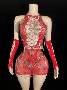 Detailed macro view of a red fishnet mini dress featuring punk silver chains and safety pins