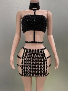 Detailansicht eines sexy schwarzen mit Strass besetzten Haltertops und Minirock-Sets