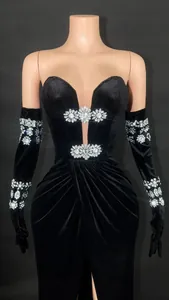 Dettaglio di un abito da sera in velluto nero con fiori di strass scintillanti e guanti abbinati.