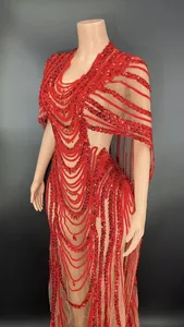 Close-up of red sequined mesh party dress with cape sleeves and intricate patterns