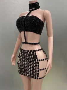 Sexy schwarzes Set aus Crop-Top mit Strasssteinen und engem Minirock auf einer Puppe.