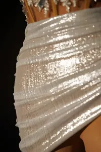 Close-up of shimmering pleated white mini skirt showing detailed fabric texture
