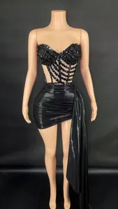 Detalle del top corsé negro con pedrería y conjunto de minifalda drapeada con pliegues