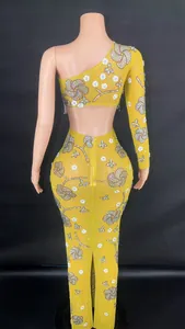 Vue détaillée du dos d'une robe de soirée jaune à paillettes et une épaule dénudée.