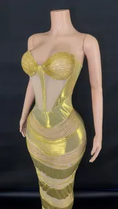 Close-up detail of golden rhinestone evening gown with shimmering mesh and chains.