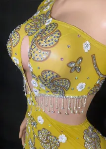 Gros plan d'une robe de soirée jaune asymétrique avec franges en strass et fleurs appliquées