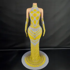 Elegante vestido de noche amarillo con pedrería plateada, cuello halter y guantes largos