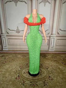 Detail of a floor-length green rhinestone evening dress with red shoulder flowers