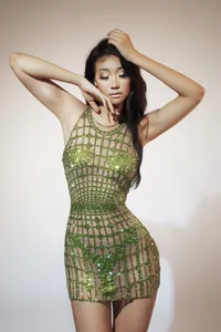 Close-up of a glamorous green rhinestone mesh mini dress on a model for performance wear