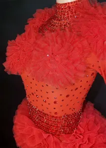Close-up of red rhinestone bodysuit with dramatic ruffled tulle shoulder and waist details.