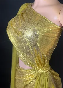 Close-up of sparkling gold sequins and elegant cutout design on a one-shoulder evening gown