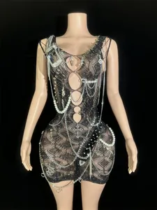 Detailed view of black mesh bodycon mini dress with safety pins and pearl chains.