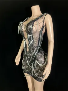 Detail of black mesh mini dress featuring punk safety pins, chains, and pearl accents.
