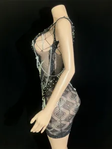Detail of a sexy black mesh backless mini dress with chains and pearl beads