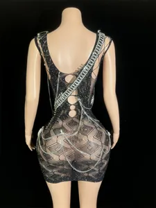 Back view of a black mesh mini dress with rhinestones, safety pins and chains details.