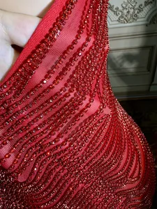 Close-up macro view of intricate red rhinestone wavy pattern on sequined dress
