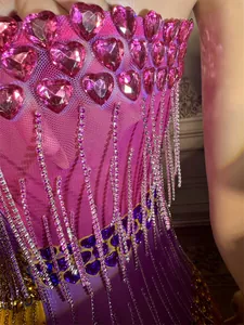 Close-up of pink heart gems and crystal fringes on a purple mesh evening party dress.