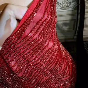 Detailed shot of a red slim-fit mini dress featuring intricate rhinestone wavy patterns