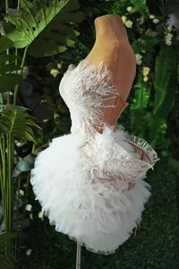 Dettaglio squisito del mini abito bianco a balze con corpetto di piume e perline