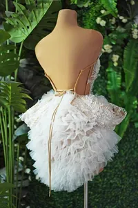 Vista dettagliata del retro di un elegante mini abito bianco a balze con lacci sulla schiena