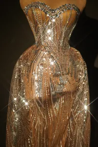 Dettaglio di un abito da sera color champagne con paillettes e scollatura di strass lucenti.