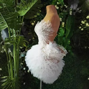 Elegante mini abito bianco monospalla con corpino di piume e gonna in tulle a balze.