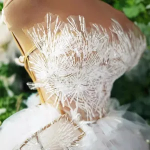 Elegante abito corto bianco con spalle scoperte, paillettes e piume bianche