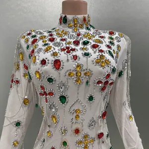 Detailed view of white high-neck dress with colorful rhinestones and silver tassels.