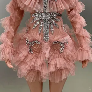 Detailed view of elegant pink ruffled mesh dress with sparkling rhinestone decor