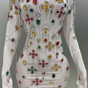 Close-up of white bodycon evening dress with colorful rhinestones and silver tassels