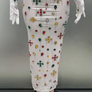 Close-up of white evening gown with colorful rhinestones and matching gloves for party.