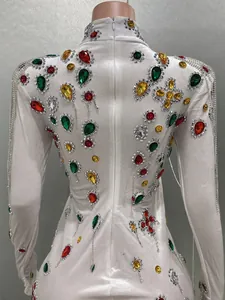 Close-up of white velvet evening dress with colorful rhinestones and silver fringe