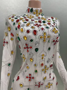 Detail of a white high-neck evening gown with colorful rhinestones and silver fringe.
