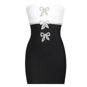 Detailed view of black and white bandage dress featuring elegant rhinestone bow decorations