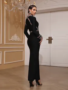 Detail of black long-sleeved evening gown with colorful gemstone accents and slim fit profile